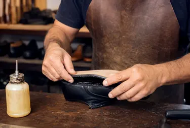 Profissional colando sola de sapato, utilizando adesivo e ferramentas.